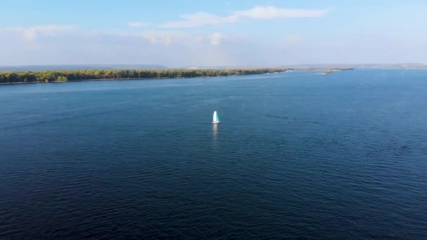 Flygjakt på segelbåt som flyter på havet till skogbevuxen strand. Tagen av drönare — Stockvideo