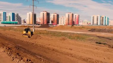 Bir yol inşa etmek için zemini dümdüz eden çalışan buldozerin yanından uçarak geçmek