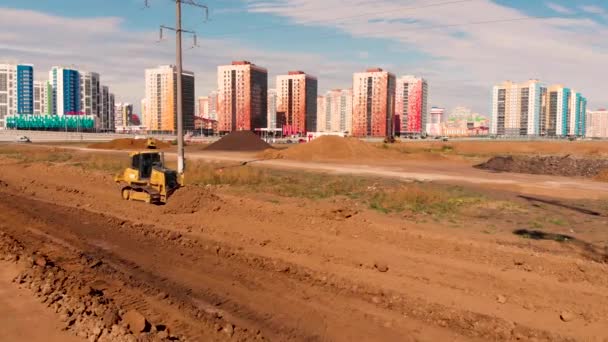 Flying past the working bulldozer that flattens the ground for building a road — Stock Video