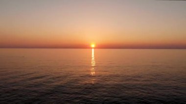 Suyun üzerinden, denizde batan güneşe doğru uçun. Gün batımında insansız hava aracı tarafından çekiliyor.