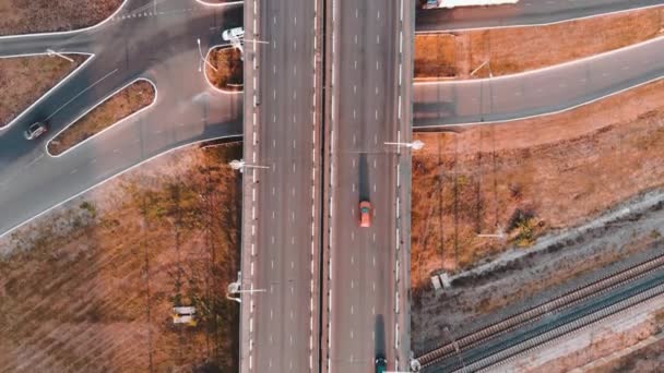 Gün batımında hareket halindeki arabalar ve tren raylarıyla yol kavşağının havadan görüntüsü — Stok video