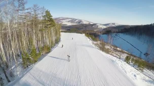 Aerial view of snowboarders riding in the mountains. — ストック動画