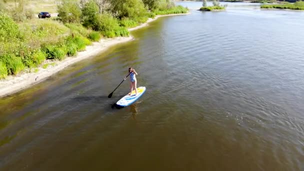 Junges Mädchen, das auf einem Surfbrett steht und auf dem See surft. Per Drohne aufgenommen — Stockvideo