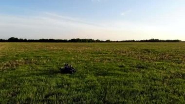 Bir adamın havadan vurulması yeşil alanda bir ATV 'ye biniyor. İnsansız hava aracı tarafından çekiliyor.