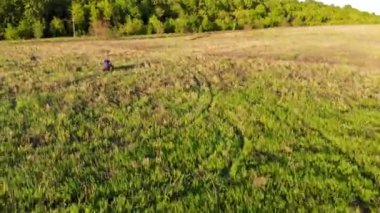 Bir adamın havadan vurulması yeşil alanda bir ATV 'ye biniyor. İnsansız hava aracı tarafından çekiliyor.