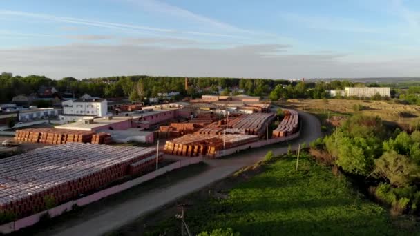 Vuelo aéreo sobre el almacén de una fábrica de ladrillos. Tomado por dron al atardecer — Vídeos de Stock