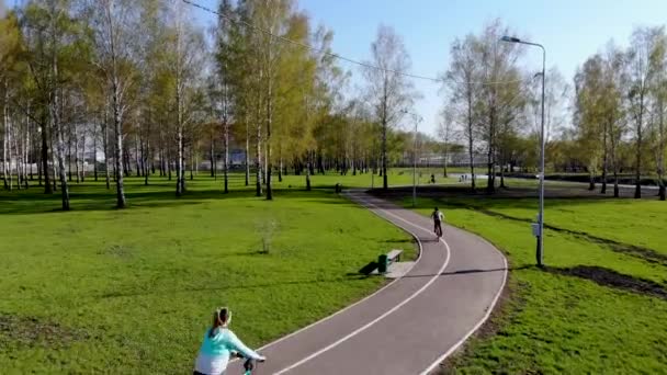 Воздушный полет для мальчика и девочки, который катается на велосипеде в парке. Снято беспилотником — стоковое видео