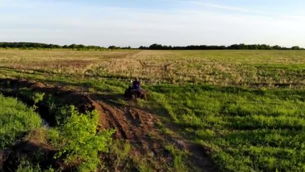 Bir adamın havadan vurulması yeşil alanda bir ATV 'ye biniyor. İnsansız hava aracı tarafından çekiliyor. — Stok video