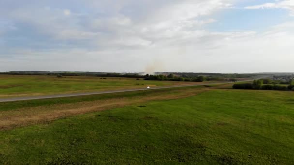 Rastreamento aéreo do carro que viaja na estrada colocada através do campo. Tomado por drone — Vídeo de Stock