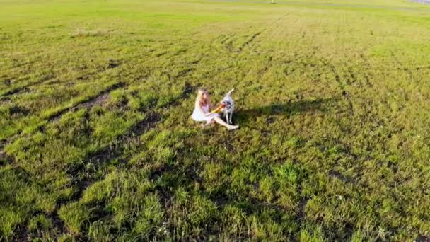 Hermosa chica pasea y juega con su perro de raza dálmata. Tomado por dron — Vídeo de stock