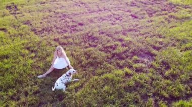 Güzel bir kız dinleniyor ve Dalmaçyalı köpeğiyle oynuyor. İnsansız hava aracı tarafından çekiliyor.