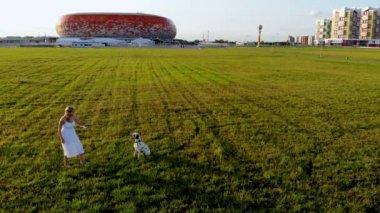 Beyaz elbiseli bir kız Dalmaçyalı köpeğiyle oynar ve onu eğitir. İnsansız hava aracı tarafından çekiliyor.