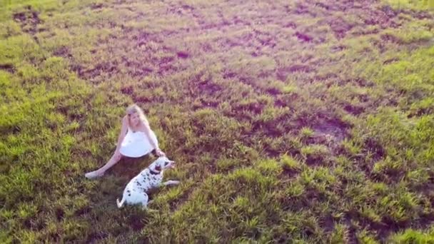 Una hermosa chica está descansando y jugando con su perro dálmata. Tomado por dron — Vídeo de stock