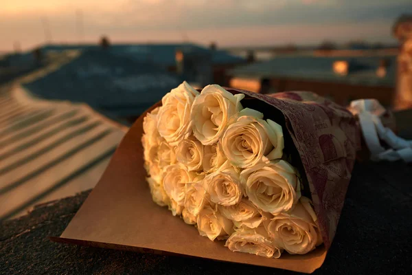 Um buquê de rosas no telhado, pôr do sol . — Fotografia de Stock