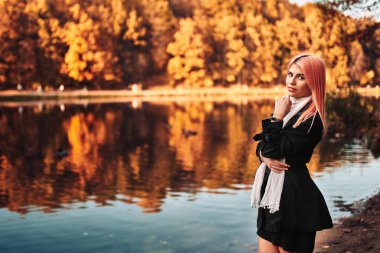 Pembe saçlı kız sonbahar parkında yürüyor.