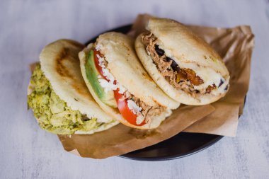 Arepa, Venezuela ve Kolombiya 'dan tipik besinler, beyaz arka planda yemeye hazır. Arepalar Desmechada eti, avokado, peynir ve fasulye ile doludur.