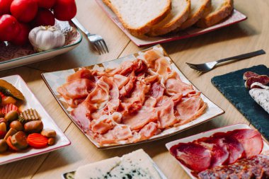 Bir masada İspanyol serrano jambonu, pa amb domates (domatesli ekmek gibi tercüme edilir) ve sarımsak