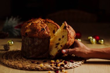 Siyah bir arka planda Panettone ve bir adam bir dilim alıyor..