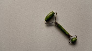 Yüz masajı için Jade Roller ya da gri kağıt arka planda gua sha. Üst Manzara. Boşluğu kopyala.