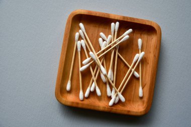Tahta tabakta bambu pamuklu çubuklar. Mavi kağıt arka plan. Sıfır atık. Yukarıdan bak. Boşluğu kopyala.
