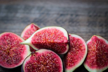 Ahşap bir masada arka plan olarak taze incir dilimlenmiş.