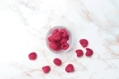 Açık mermer zemin üzerinde bir bardakta ahududu, üst manzara