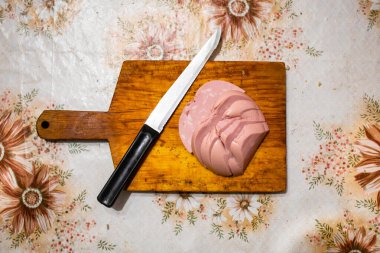 Tahta kesme tahtasının üzerinde dilimlenmiş sosis. Eski bir kır masasını kesiyorum. Yukarıdan görüntüle