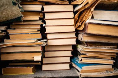 Eski püskü bir kitap yığını eski bir ahşap masanın üzerinde yatıyor.