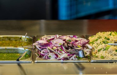 Falafel barındaki malzemeler. Metal sebze maşasıyla soğan.,