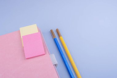 Mavi arkaplanda defter ve ofis malzemeleri var.