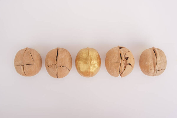 Другая концепция. Сильный грецкий орех выделяется золотом на фоне треснувших орехов
.