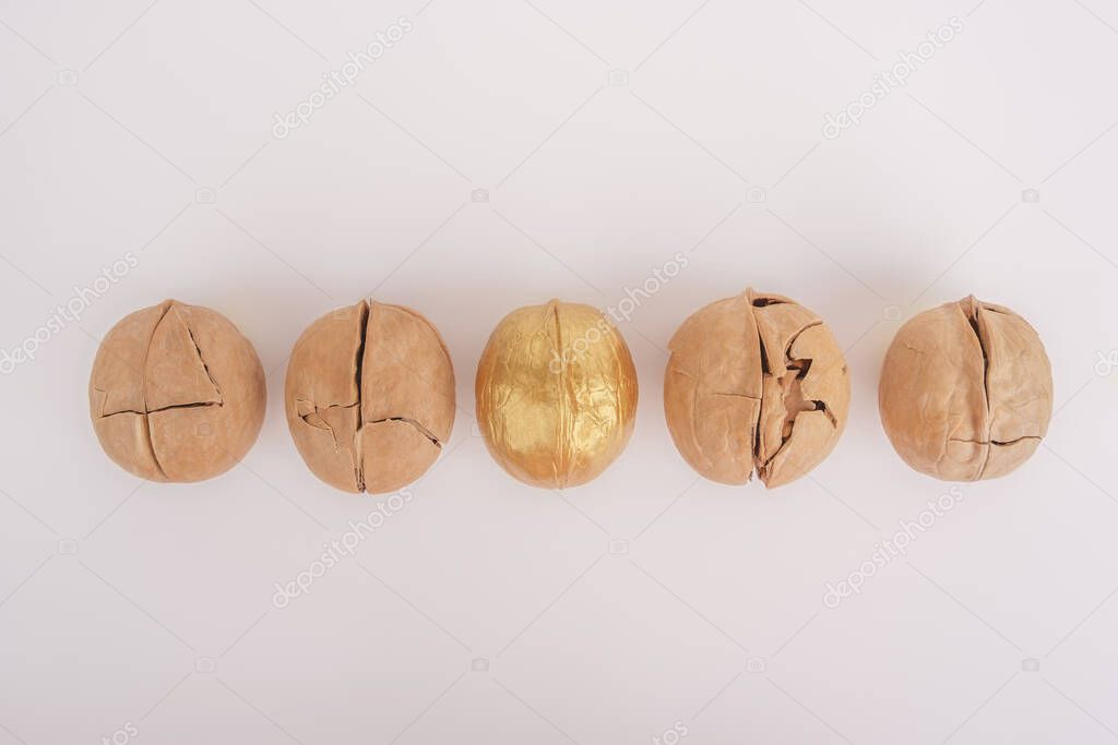 Different concept. A strong walnut is highlighted in gold against a background of cracked nuts.