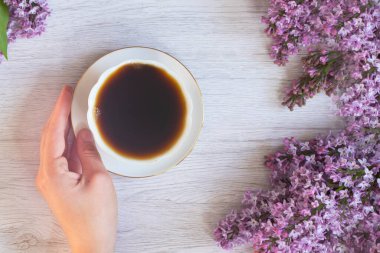 Leylak dalına yakın çekim, kahve ya da çayla el ele tutuşan bir fincan, klasik tarzda bir hayat. düz yat