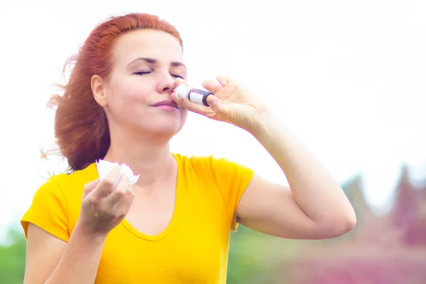 Close-up. A sick woman drips into her nose, drips, sprays from nasal congestion, colds and flu. The female inhales fresh air, a nasal nose during a cold.