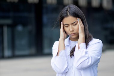 Ciddi bir Asyalı kız öğrenci baş ağrısı çekiyor. Beyaz elbiseli, gömlekli, hayal kırıklığına uğramış genç bir kız. Kötü haber, hayal kırıklığına uğramış negatif duygu. Sağlık ve kafa sorunları