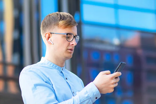 Bir mesaj yazan öğrenci, yakışıklı Avrupalı bir adam SMS mesajı gönderiyor, cep telefonuna SMS gönderiyor. Gözlüklü genç iş adamı, cep telefonuna bakıyor..