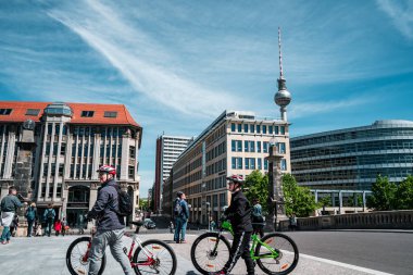 Berlin, Almanya - 12 Mayıs 2019: Sokakta gezinen insanlar ve bisikletçiler ile şehir binaları arasında Berlin Tv Kulesi.