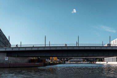 Berlin, Almanya - 14 Mayıs 2019: Gündüz leri kentte köprüden geçen insanlar.