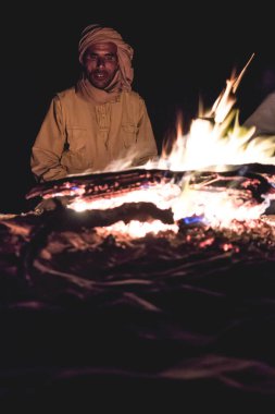 Tunus 'un Sahra Çölü' ndeki şenlik ateşinin önündeki adam.