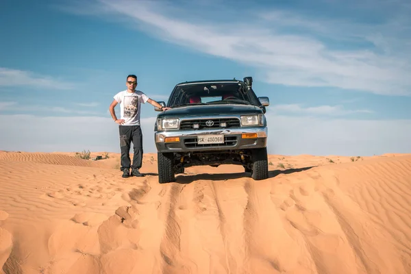 年轻英俊的男子在撒哈拉沙漠拍照 丰田40跑车在沙漠冒险之旅 — 图库照片