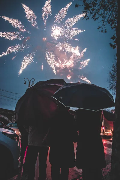 People looking the fireworks under the rain