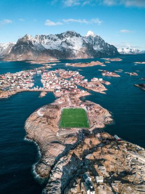 Dağların üzerindeki Atlantik Okyanusu 'ndaki Soccerfield, Henningsvaer, Lofoten Adaları, Norveç. Drone hava görüntüsü