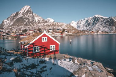 Dağların üstündeki göldeki kırmızı ev. Norveç, Lofoten Adaları 'nın muhteşem manzarası. Reine Balıkçı Köyü