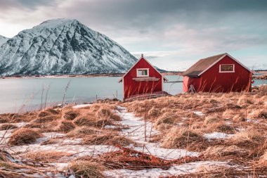 Dağların üstündeki göldeki kırmızı ev. Norveç, Lofoten Adaları 'nın muhteşem manzarası