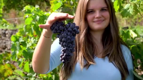 Молодая красивая девушка улыбается и держит в руке кучу винограда — стоковое видео