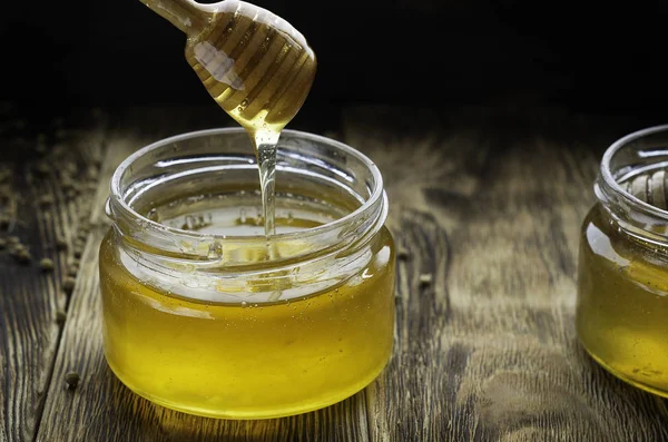 蜂蜜の木製テーブル木製蜂蜜ディッパーとガラスの瓶で — ストック写真