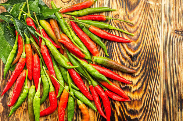 Top view of red green hot chilli pepper on a wooden surface free space on the right