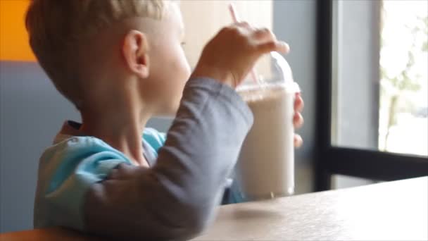Ребенок пьет молочный коктейль через соломинку — стоковое видео