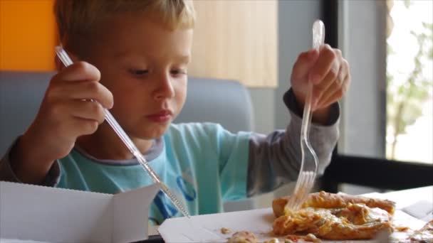 Primer plano de un niño lindo comiendo pizza. niño de cuatro años comiendo una rebanada de pizza — Vídeo de stock