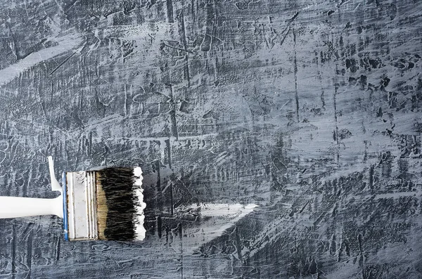 the brush in black and white paint on the background of a concrete painted gray background at the bottom left.